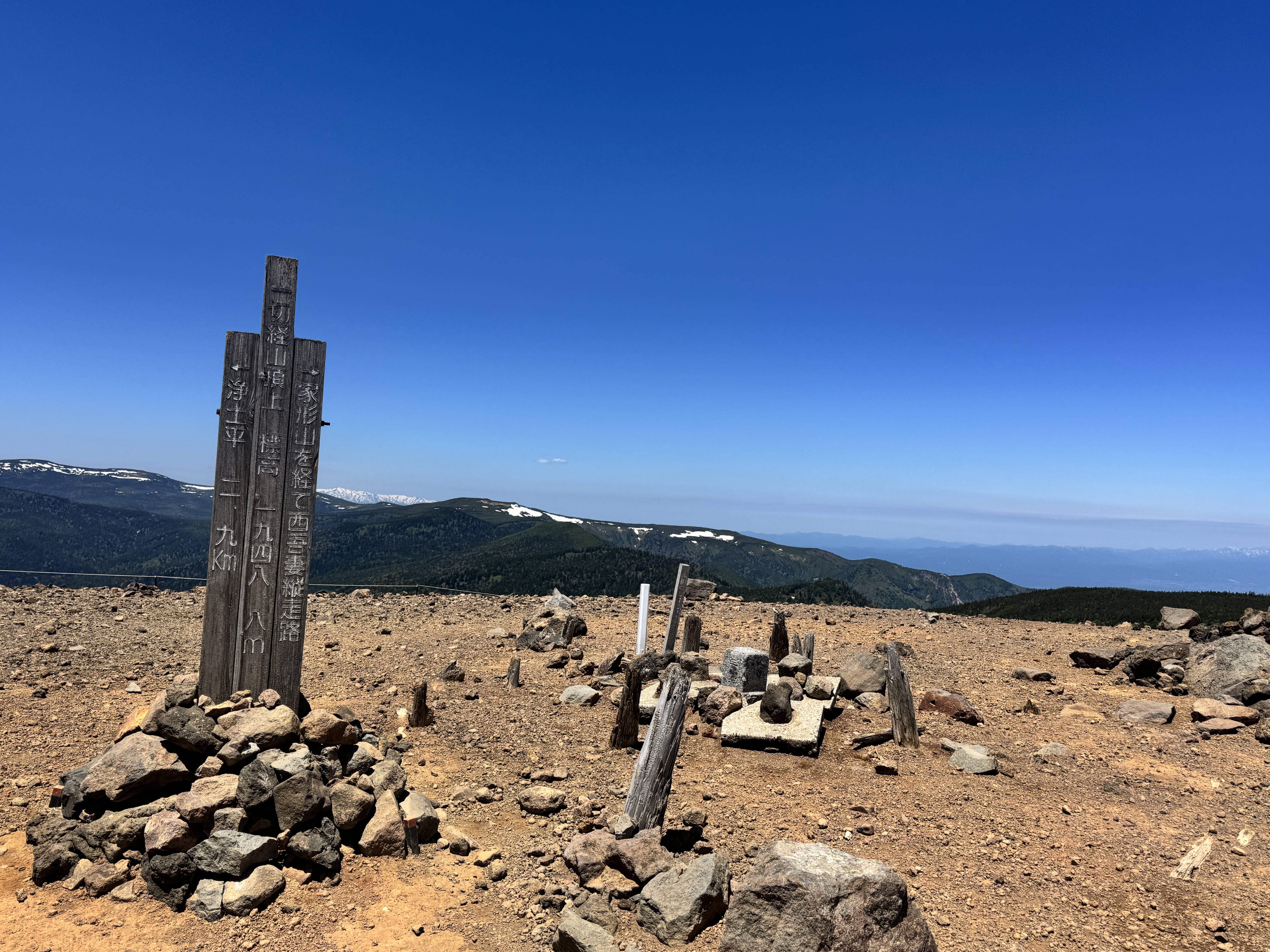 強風のなかで佇む一切経山の山頂標識